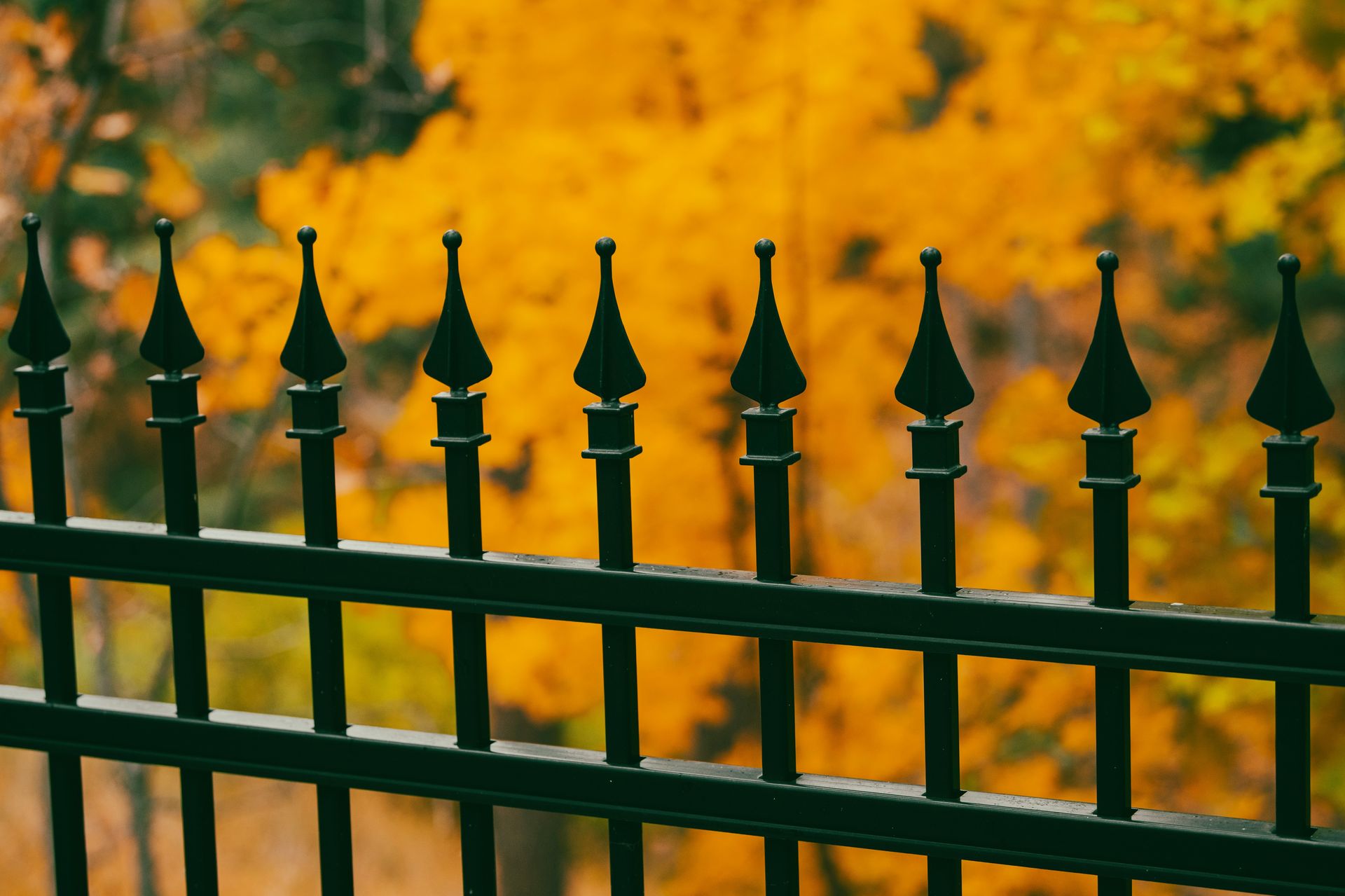 a group of black and gold fence posts with a yellow and orange background