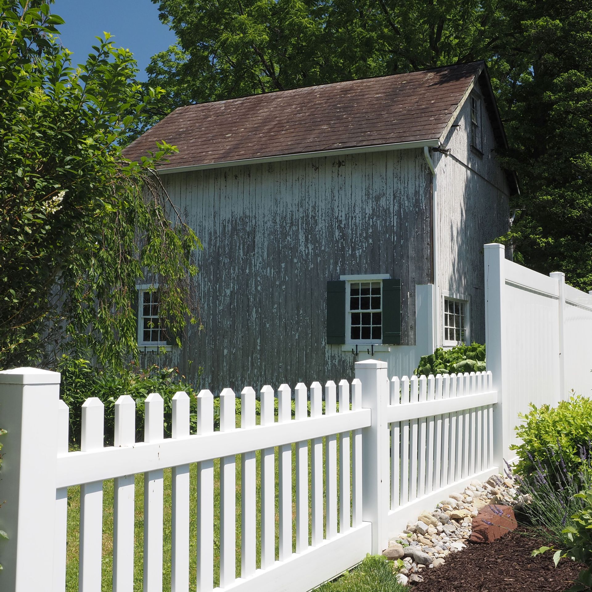 Rustic barn with white picket fence and lush greenery in Doylestown, PA.